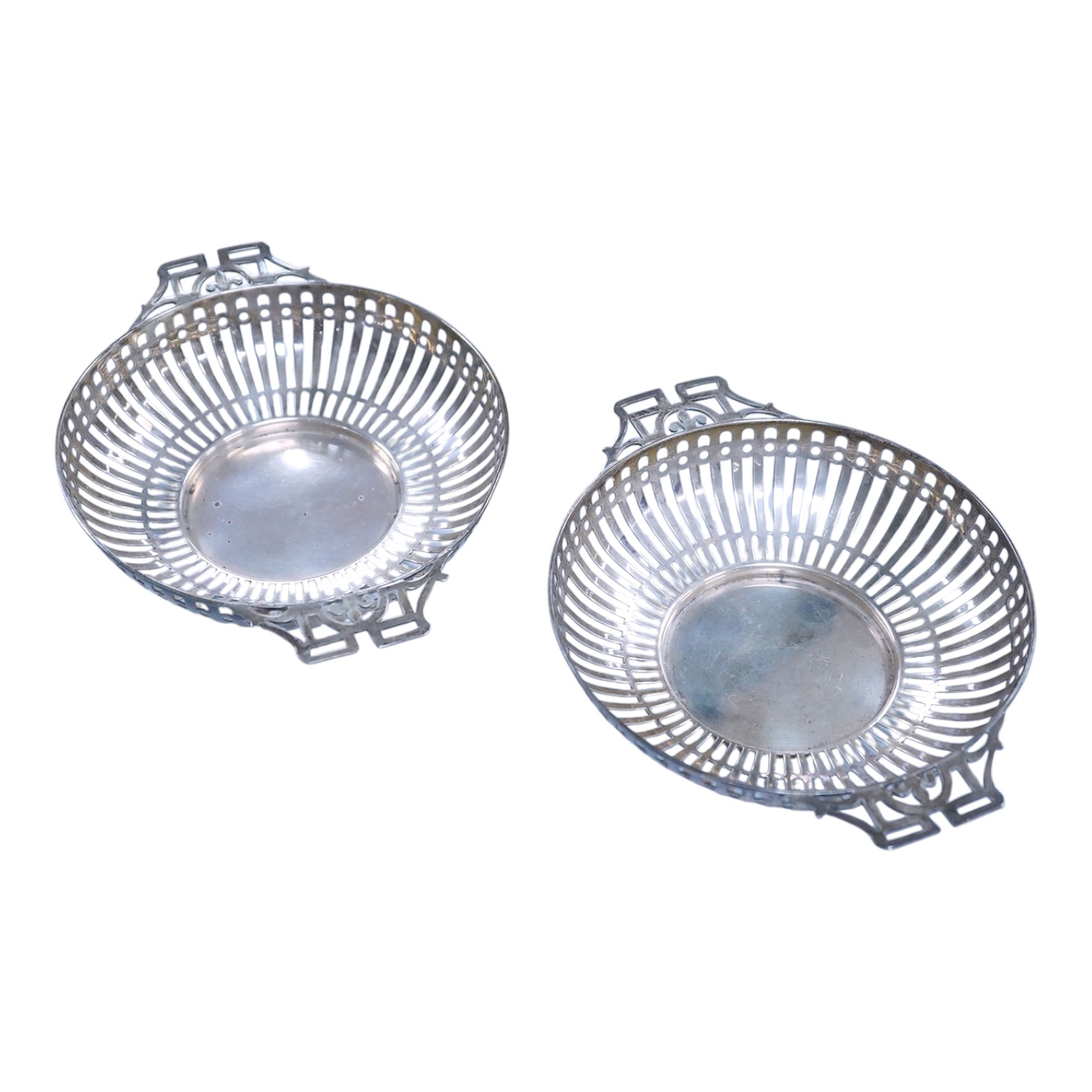 A pair of George V pierced silver two handled bonbon dishes, by Mappin & Webb, Birmingham, 1910, diameter 16.6cm over handles, possibly lacking glass inserts, 6.1oz.